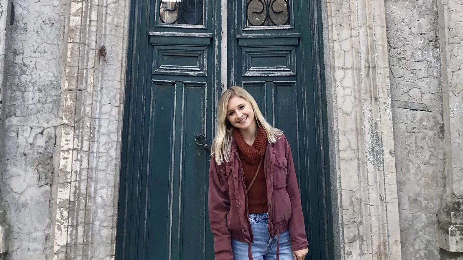 Grace Keegan stands in front of an old door on a stone building