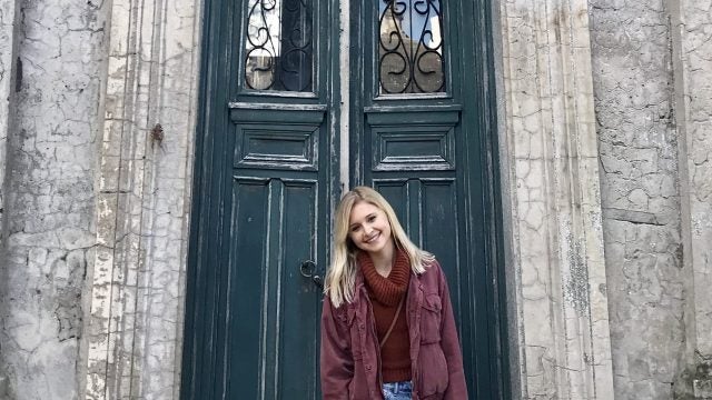 Grace Keegan stands in front of an old door on a stone building