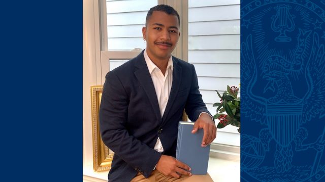 Isayah Henry wears a blazer and holds a book