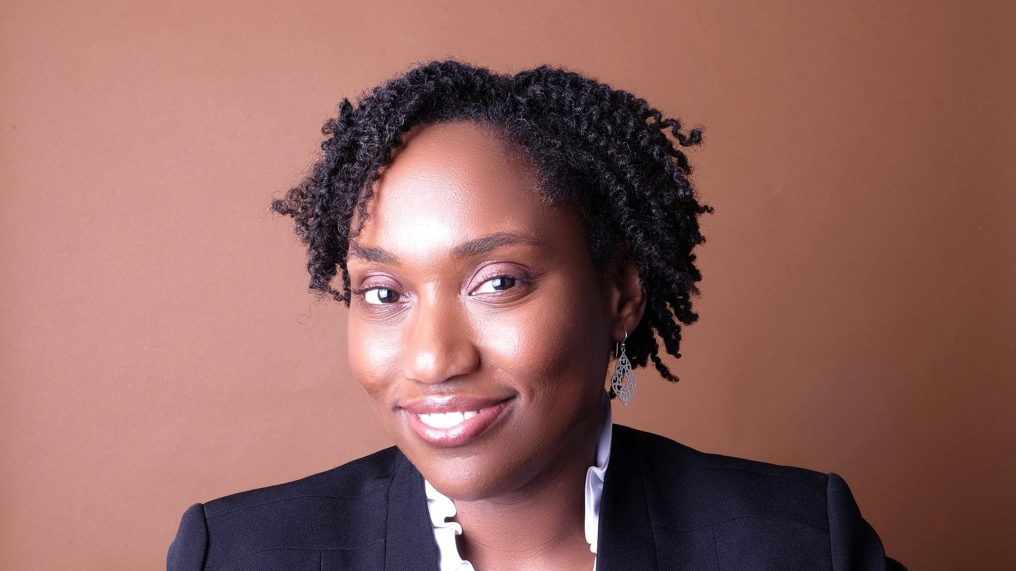 Marcia Chatelain wears a blazer in front of a brown background