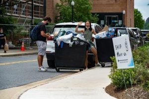 Students stand near their bin and wave a the camera