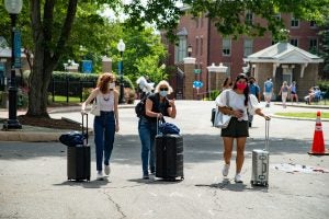 Students and a parent with suitcases walking through Healy Circle