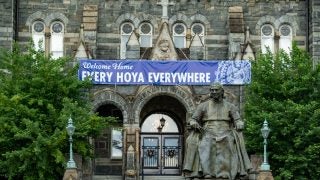 John Carroll statue in front of Healy Hall with the sign &quot;Welcome Home Every Hoya Everywhere&quot;