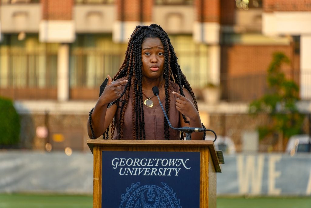 Nile Blass speaks from a podium with a "Georgetown University" sign