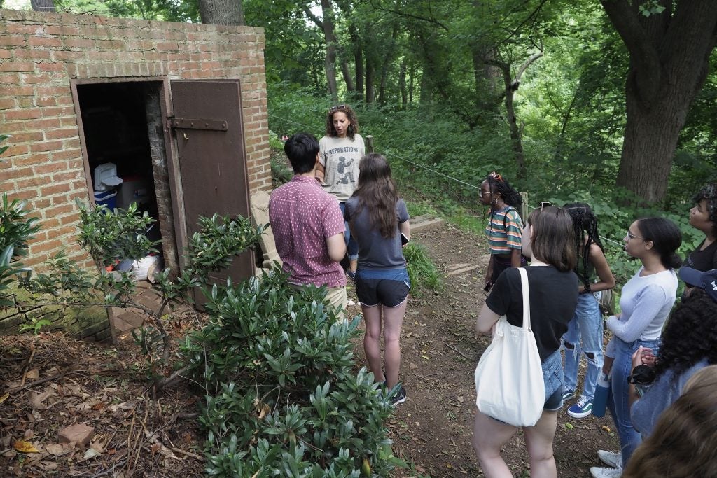 Students listen to Lisa Fager discuss the brick building to her left