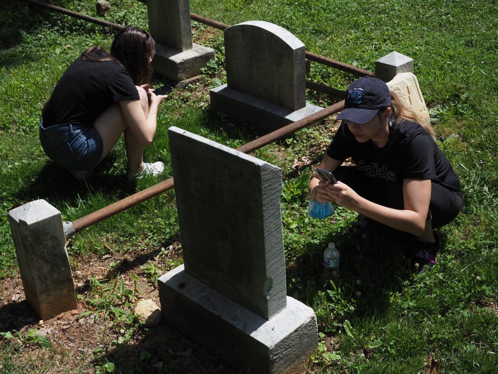 Students facing different directions log headstone inscriptions