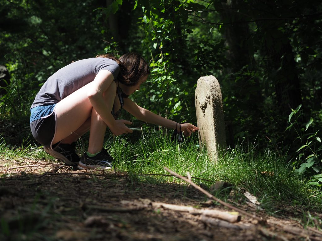Crouching student looks at headstone 