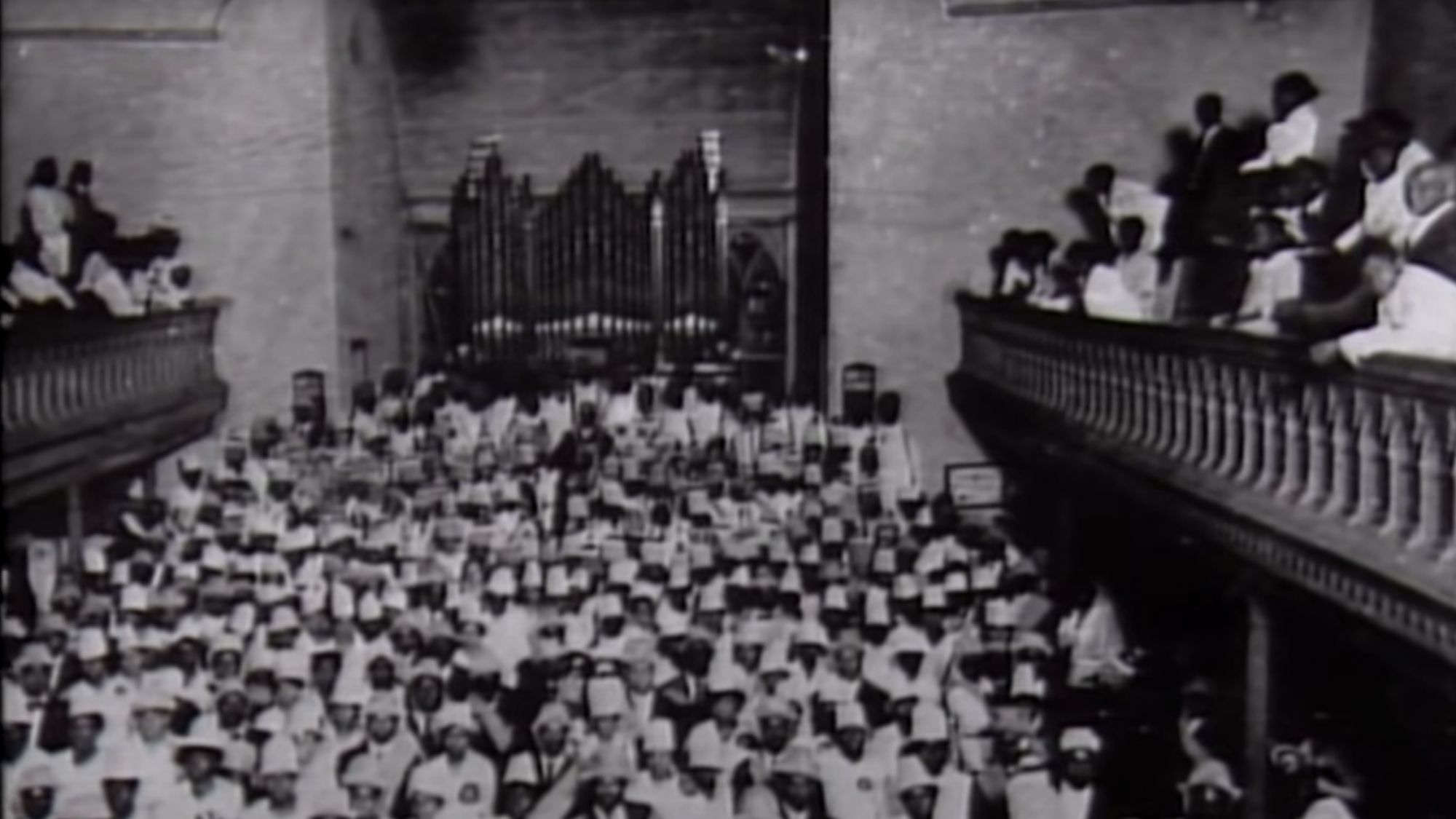 Large crowd in between two balconies in front of a church organ