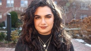 Headshot of Alanna Kronk with brick patio and buildings in the background