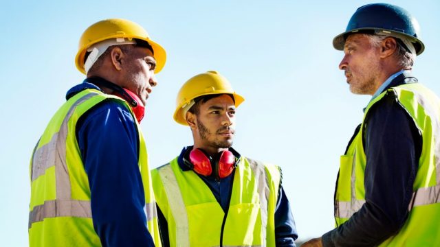 Men in neon vests and hard hats talking