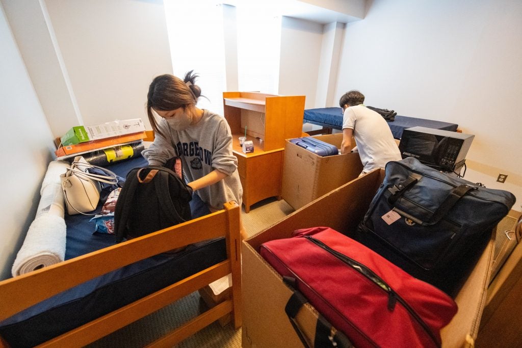 Student unpacks with her father indoors