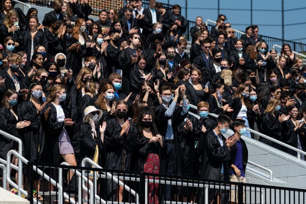 Students in on bleachers put on black robes