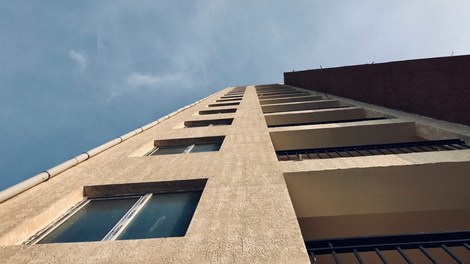 Side of a cement building looking up toward a blue-gray sky