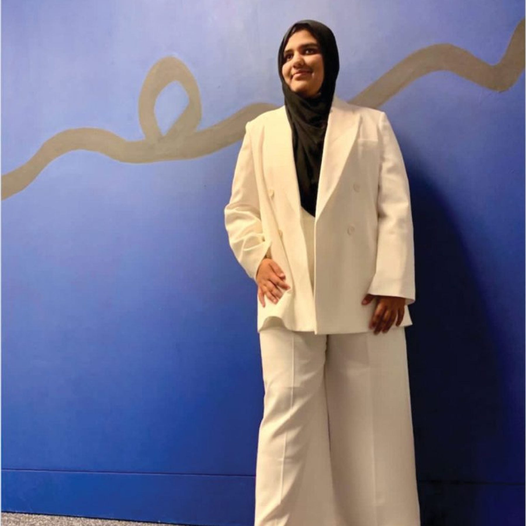 Khansa Maria standing in front of a blue wall