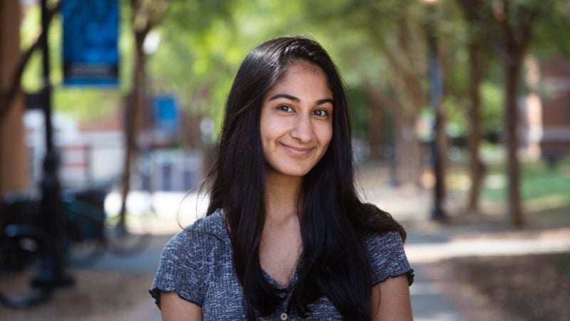 Rishma Vora wears a dark gray shirt standing outside