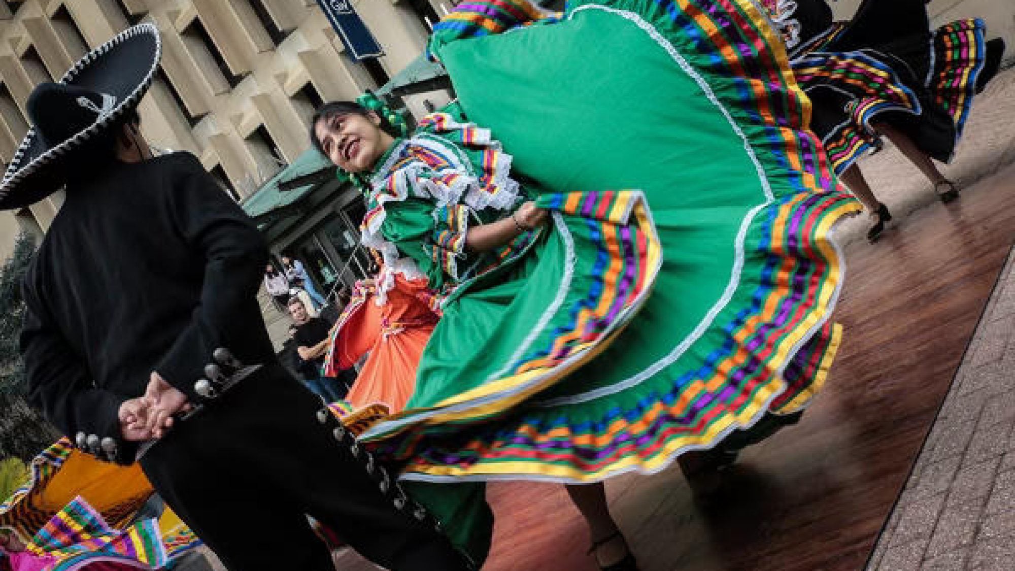 Ballet Folklorico Mexicano de Georgetown dancers twirl in colorful green and orange costumes.