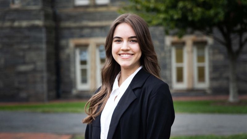 Emma Rose wears a black blazer and white blouse outside