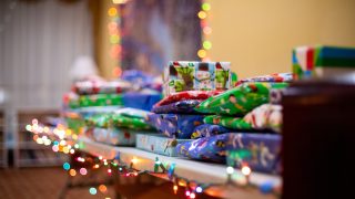 Wrapped gifts on a table with a string of multi-color lights