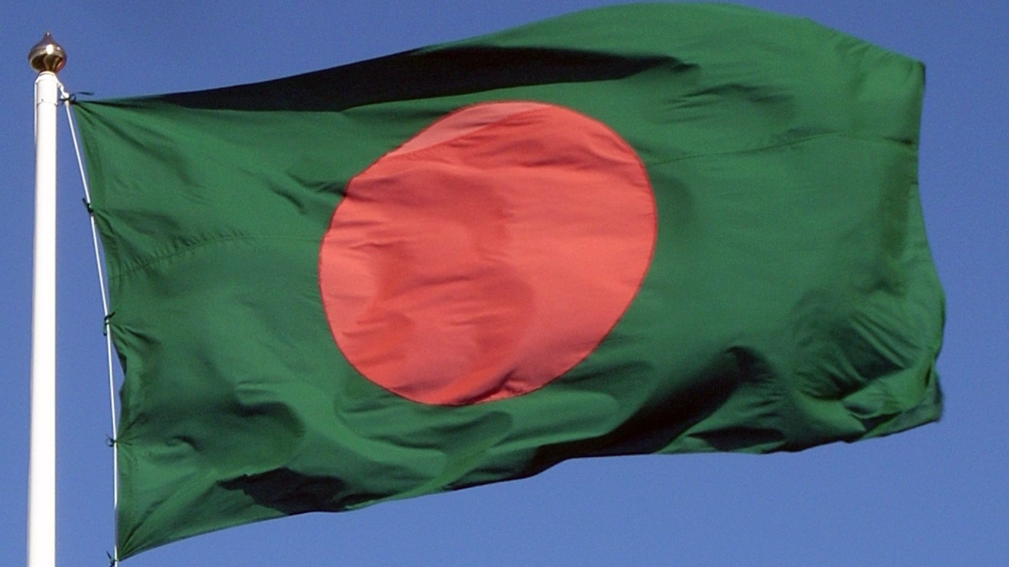 The flag of Bangladesh flying in front of a blue sky