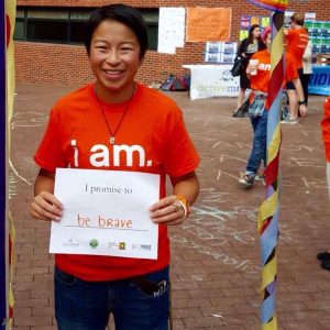 Grace Smith in Red Square wearing an orange "I am" T-shirt and holding a sign that says "I promise to be brave"