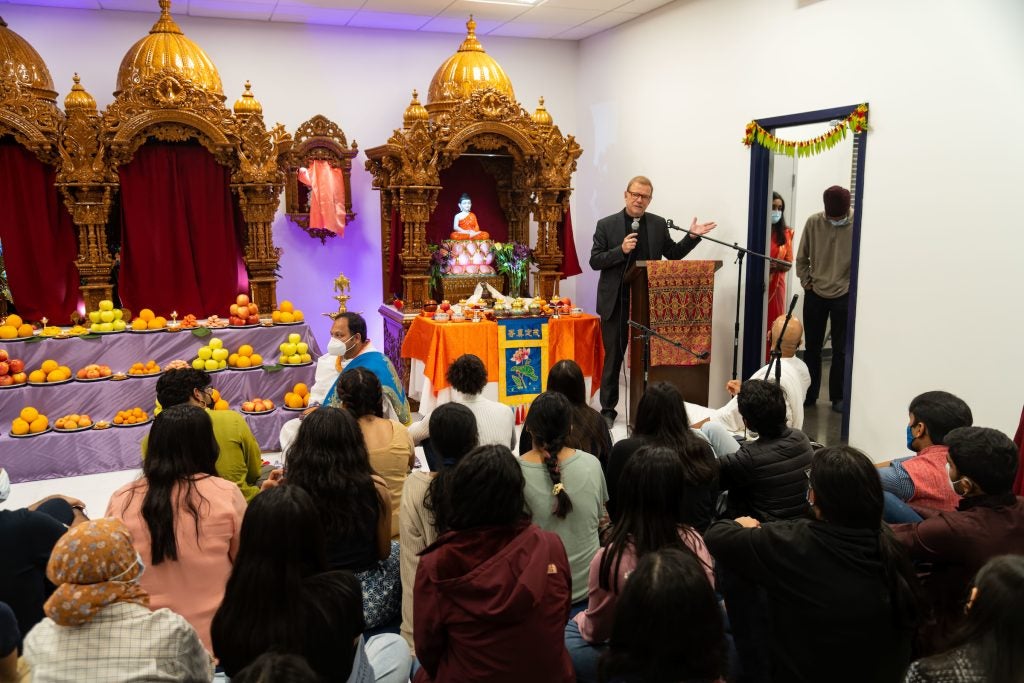 Fr. Greg stands behind a podium in front of the shrines of the Dharmic Meditation Center