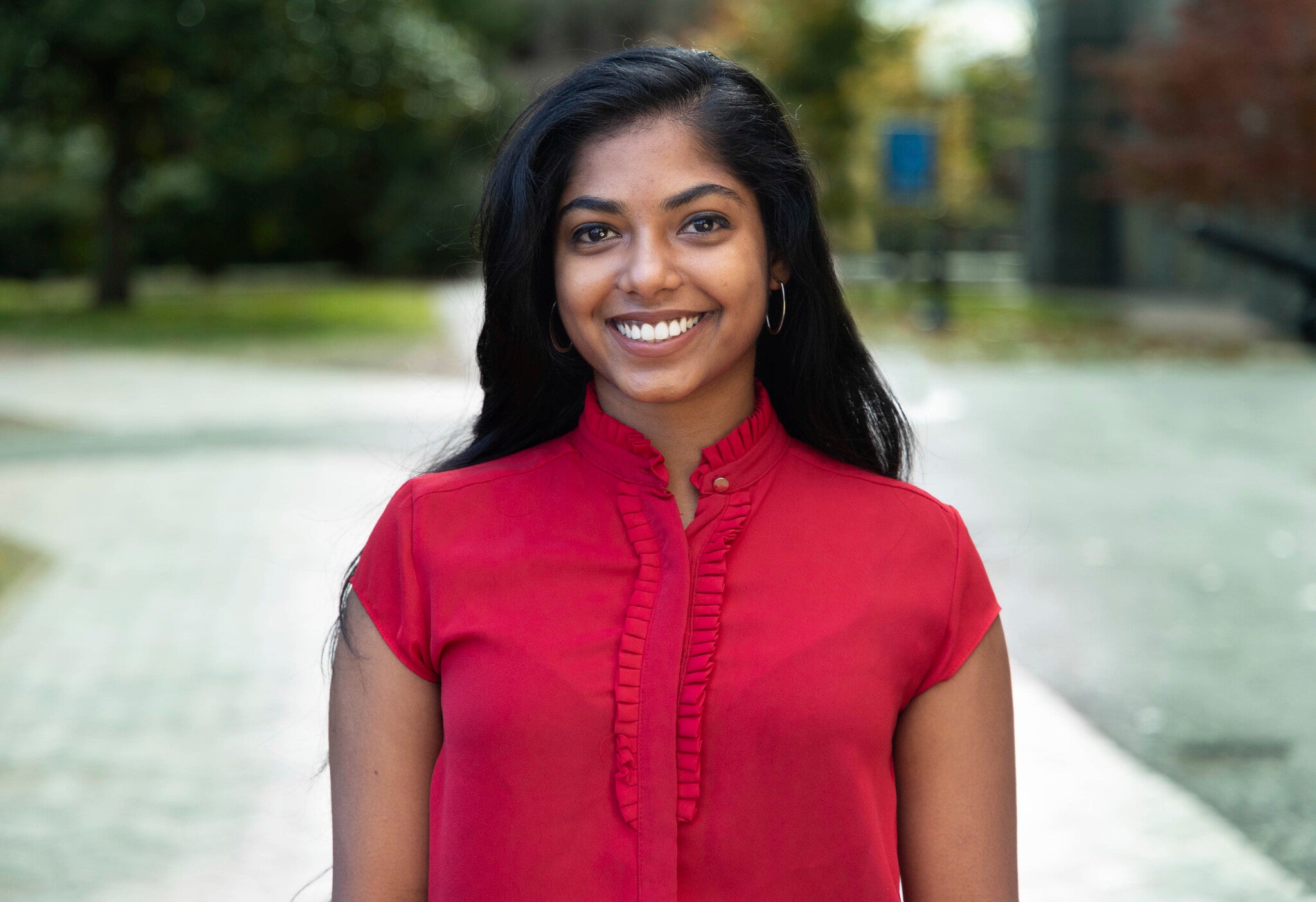 Ashanee wears a red blouse for a headshot outdoors