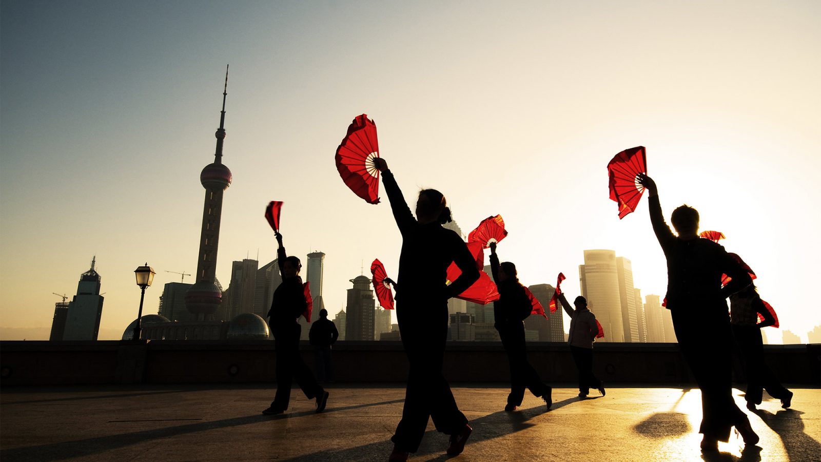 Dancers with red fans in front of Shanghai skyline