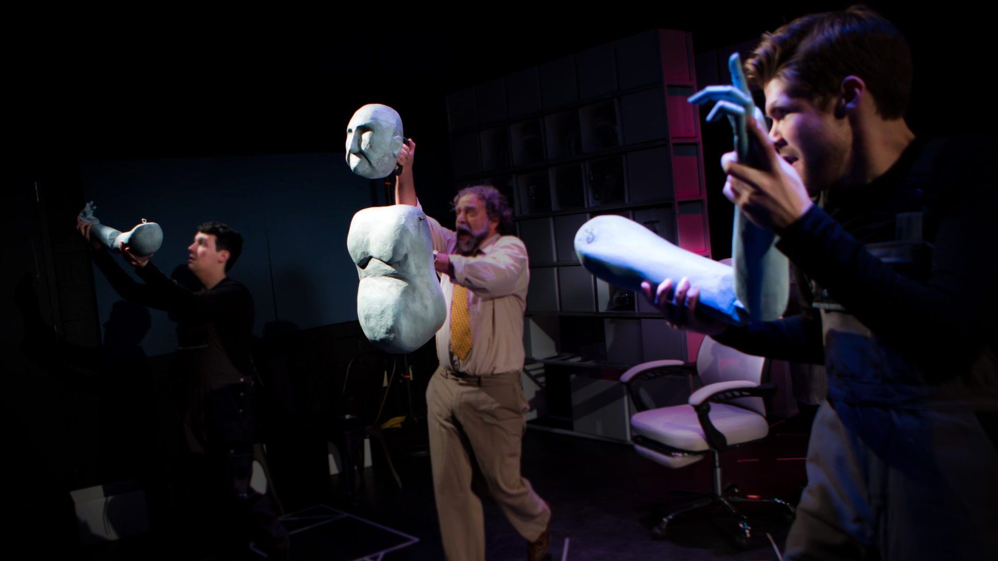 Actors hold up the head, torso and two arms of a puppet