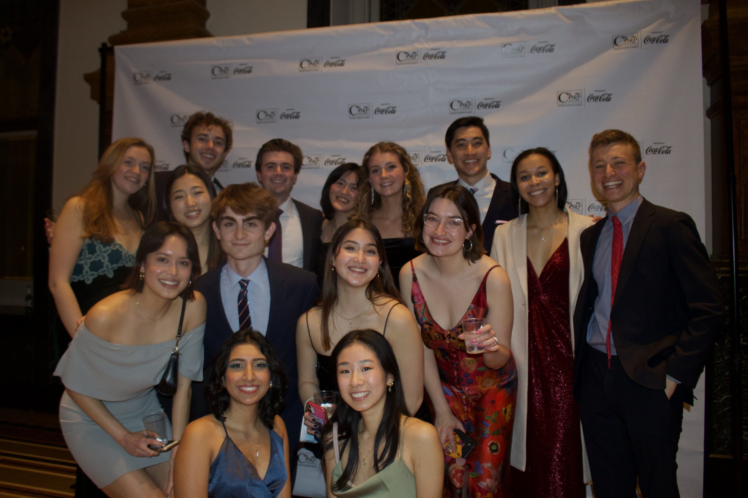 Group of students in front of a large branded Corp photo background