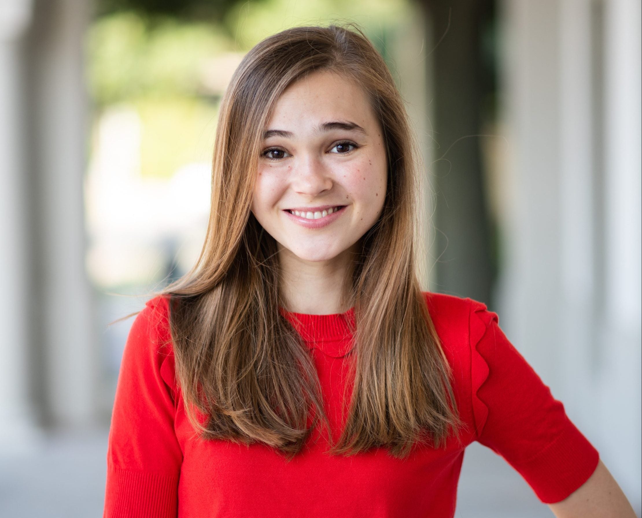 Jordan Kramer wears a red sweater in a headshot outside