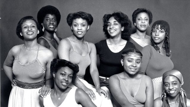 Black and white image of nine women in dance clothes