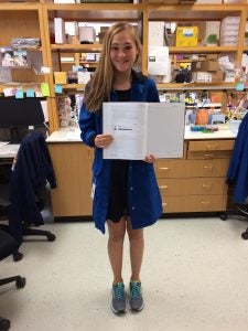 Jordan Kramer stands in a lab holding open a report