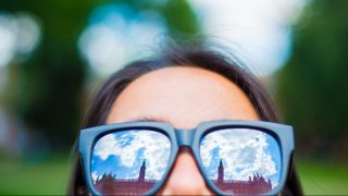 Healy Hall is reflected from a student&#039;s sunglasses