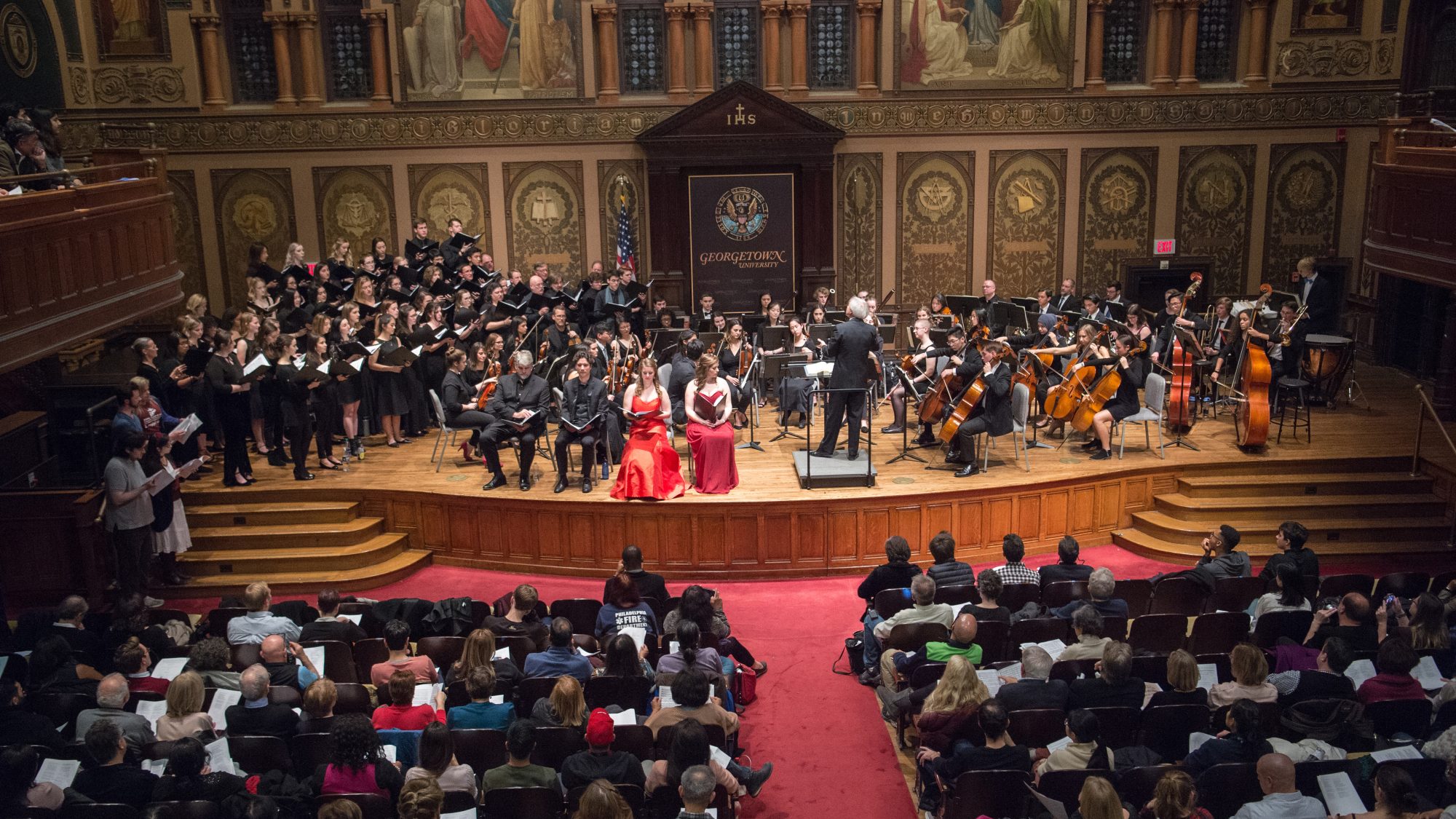 Members of the Georgetown University Orchestra and the GU Concert Choir perform together onstage in a packed Gaston Hall.