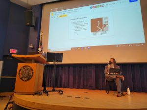 Student giving a presentation behind a podium with a powerpoint slide