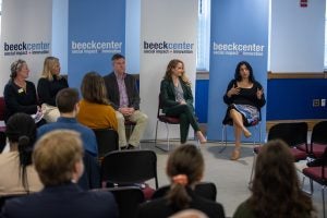 Panelists look at one of their fellow speakers in front of blue and white "Beeck Center" banners