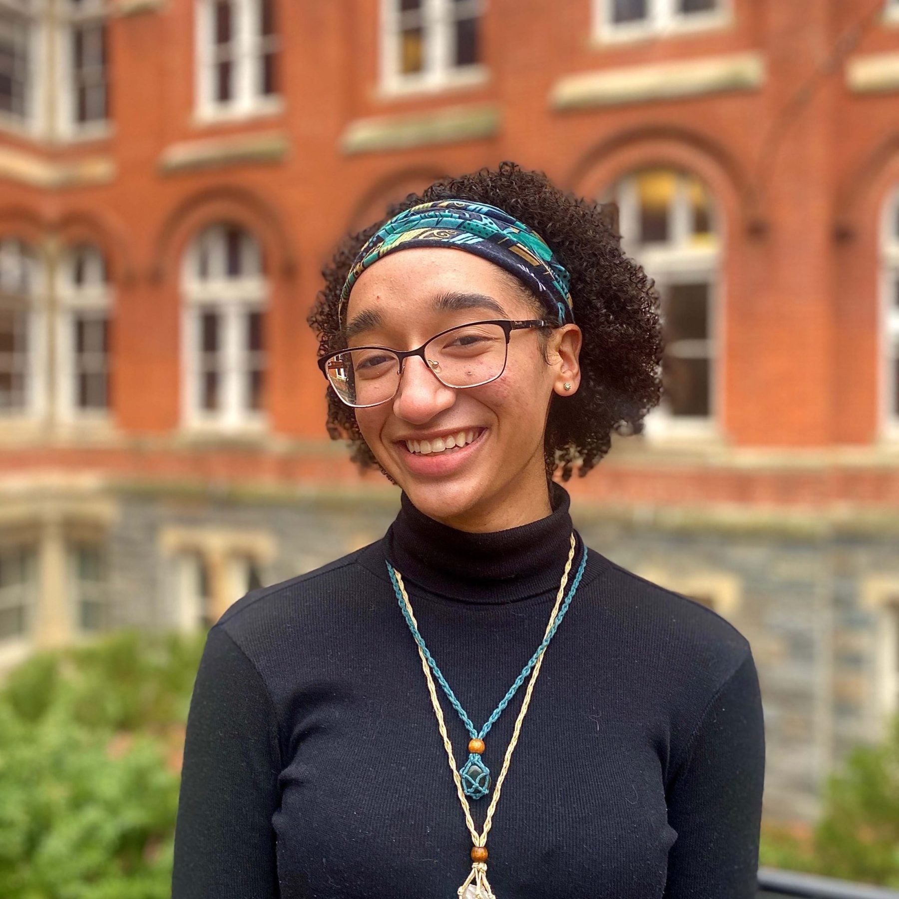 Olivia Henry wears a black turtleneck and blue headband and glasses