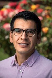 Headshot of Abel Cruz Flores in front of flowers