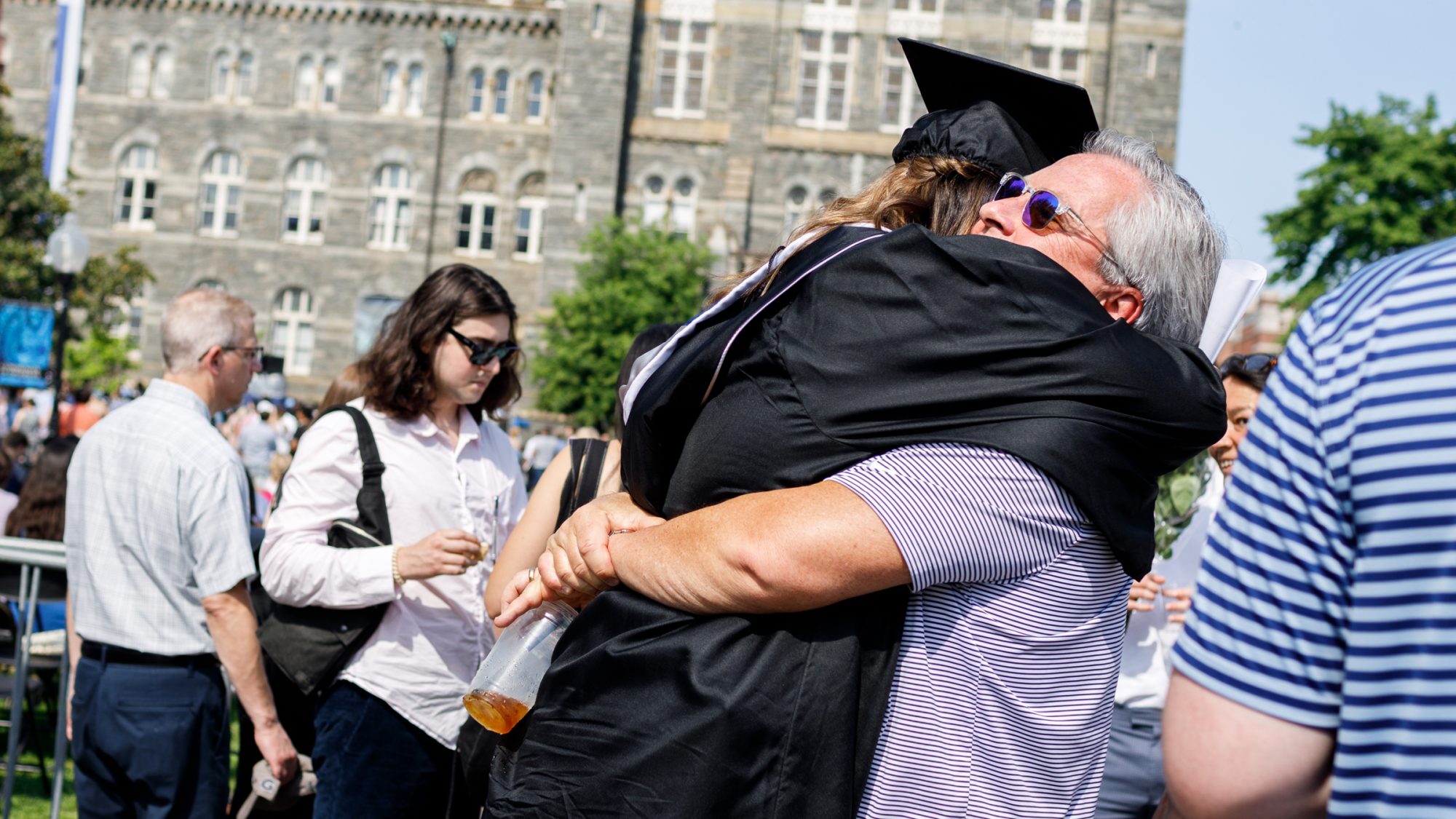 Graduating student in cap and gown hugs her dad