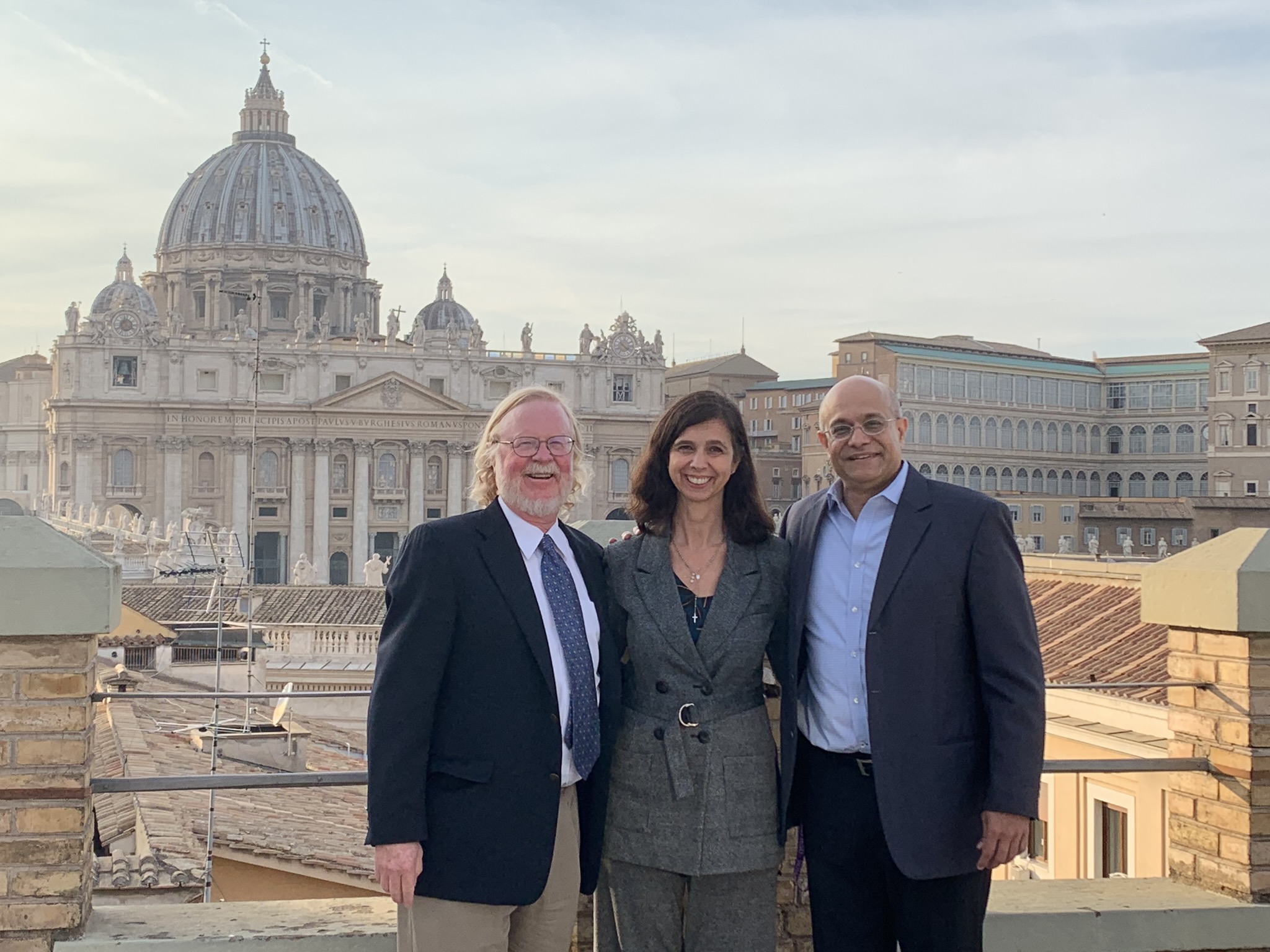 Three professors stand in front of the Vatican