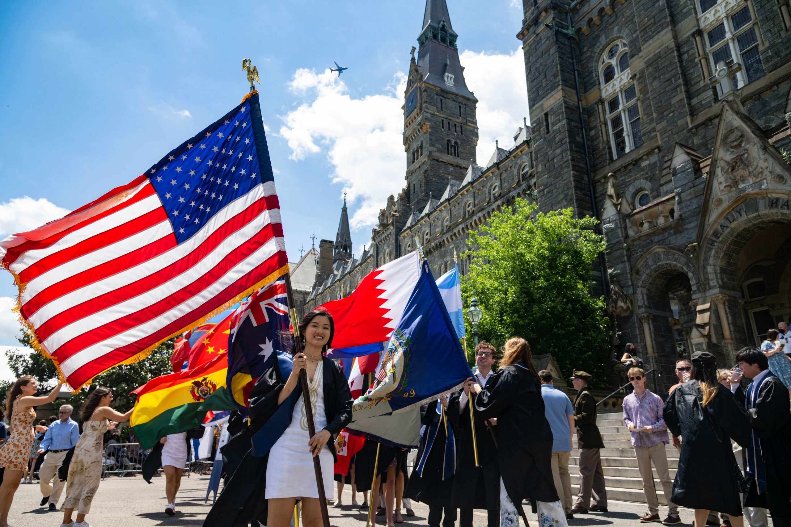 Students hold flags from different countries in front of Healy Hall