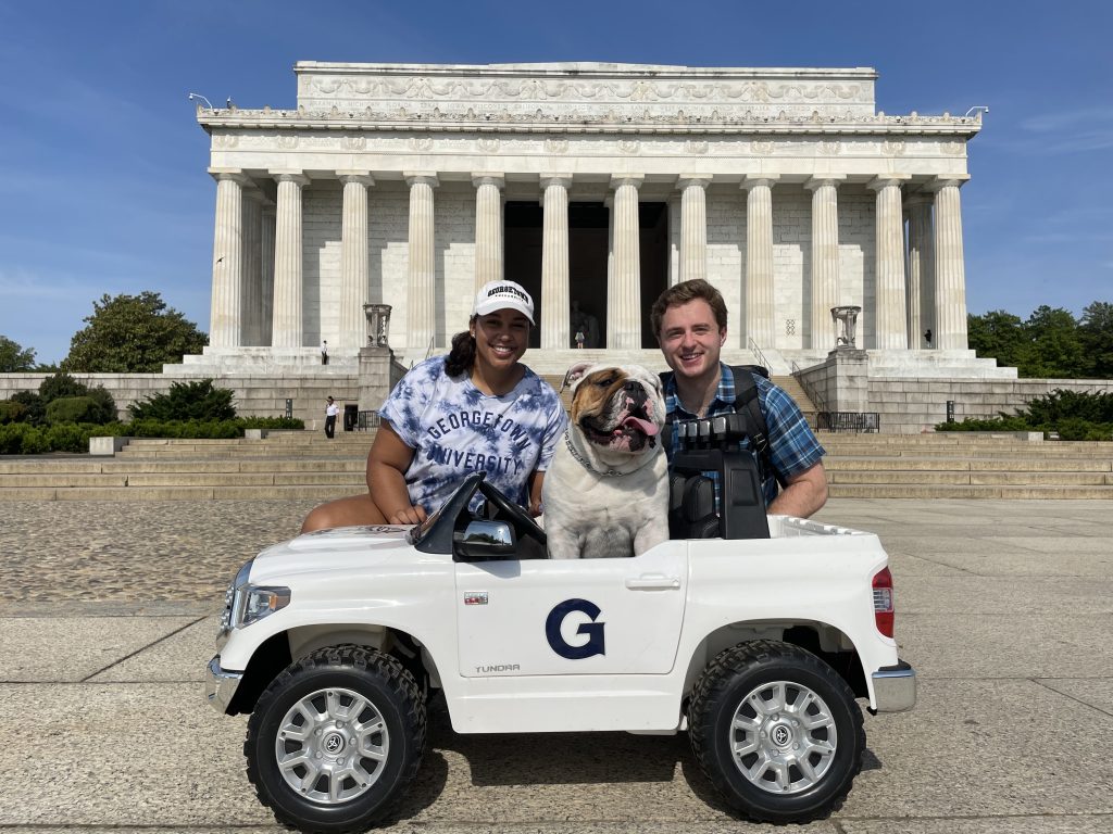 Jack the Bulldog in his toy jeep in front of the Lincoln Memorial