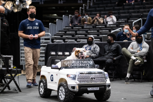 Kirk holds a remote control while Jack sits in a toy Jeep at a basketball game