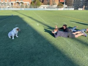 Krik lays on a field taking a photo of Jack