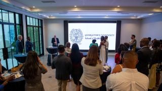 Crowd of people see presentation with a projection of the text &quot;Georgetown University School of Health&quot;