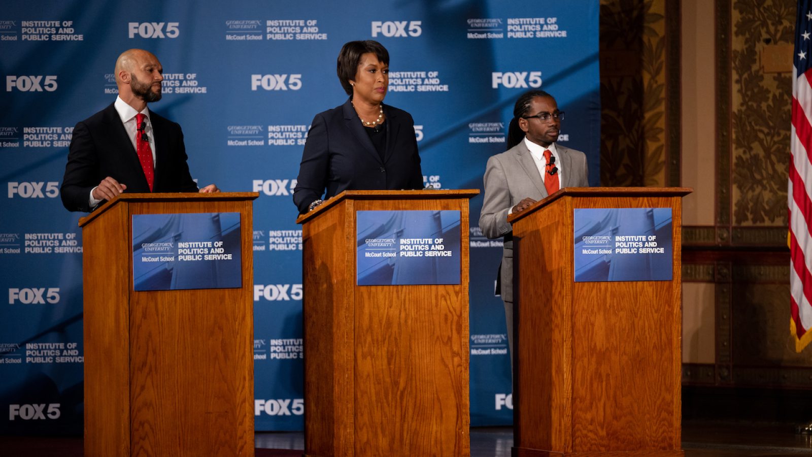 An image of three of the Democratic candidates running for mayor of DC behind three podiums in Gaston Hall during a live televised debate.