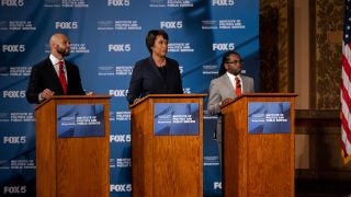 An image of three of the Democratic candidates running for mayor of DC behind three podiums in Gaston Hall during a live televised debate.