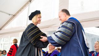 President DeGioia and a Ph.D. graduate shaking hands on stage