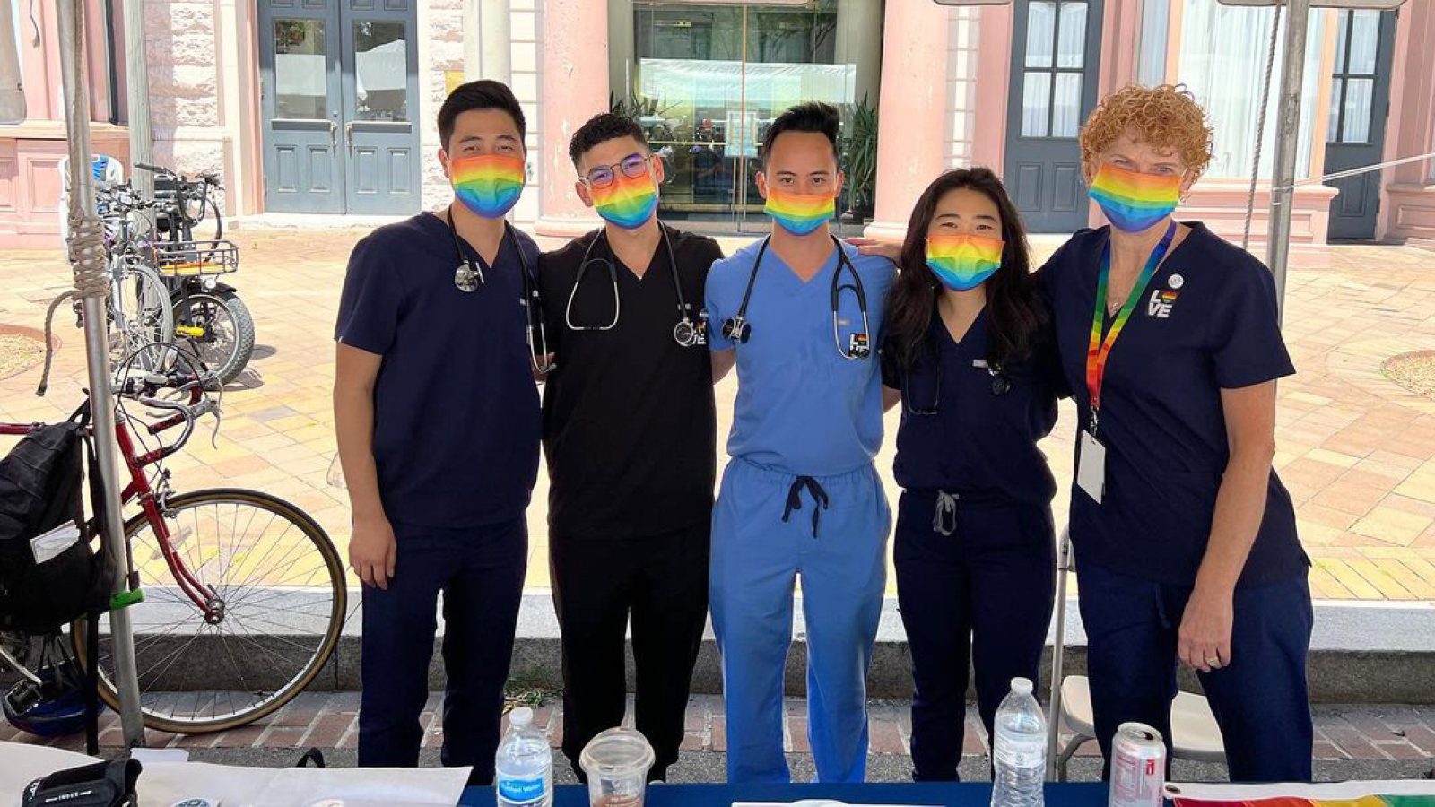 Five medical students wear rainbow-colored masks and pose together at a DC Pride Festival