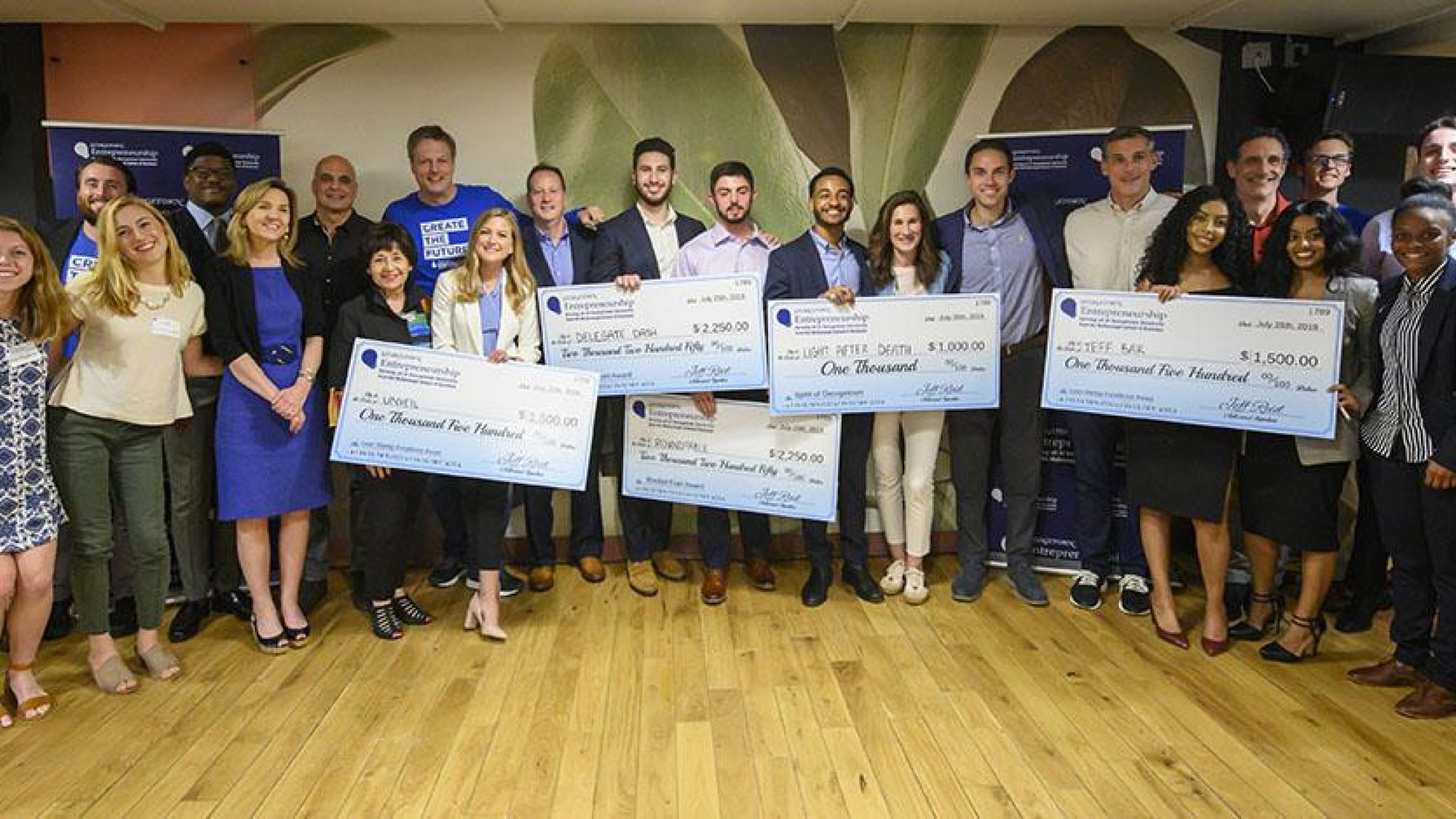 Members of the 2019 Summer Launch Incubator, some holding large checks.